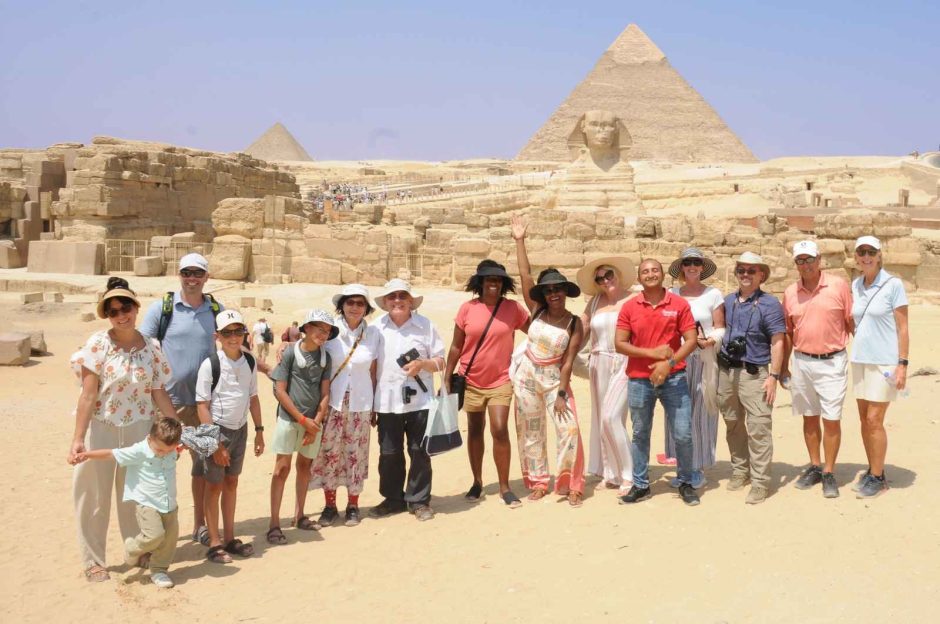 Cairo, Alexandria & Nile Cruise Tour group with Ramses Tours posing at the Giza Pyramids and Sphinx in Egypt.