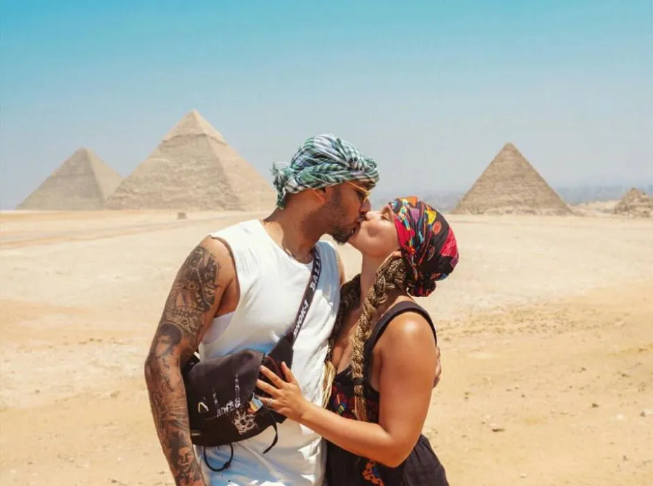 A romantic couple kissing with the Great Pyramids of Giza in the background during a private Egypt tour.