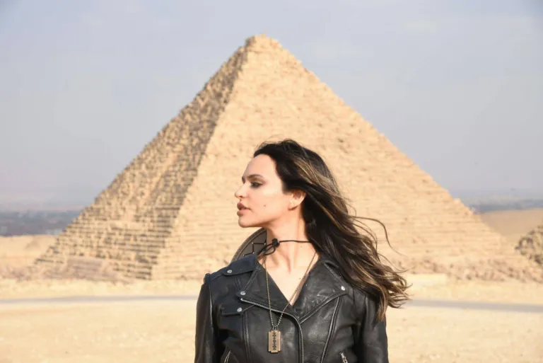 Portrait of a woman in a black leather jacket posing in front of a Great Pyramid at the Giza plateau, Egypt.