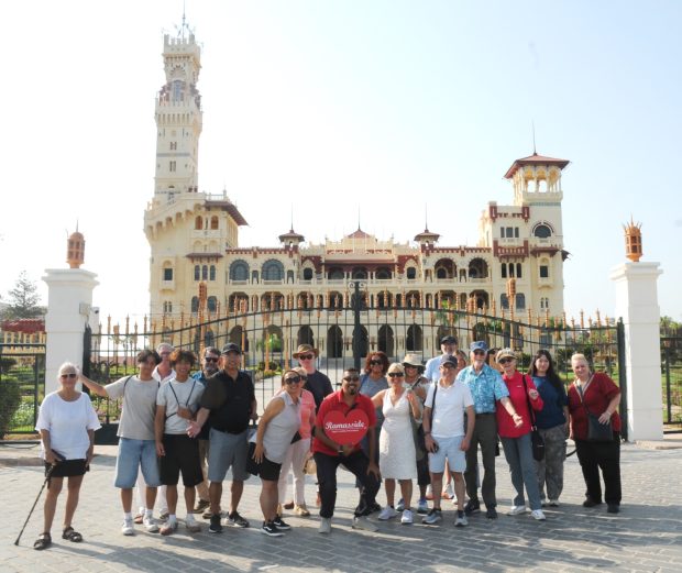 A diverse group of tourists on a guided Alexandria day trip posing in front of the majestic Montaza Palace (Al-Haramlik).