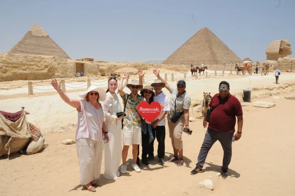 Tourists enjoy cairo and alexandria tour packages at Giza Pyramids and Sphinx with a guide on a bright sunny day.