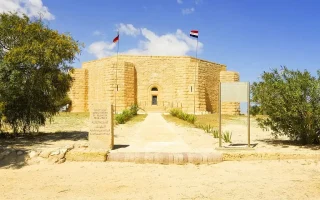 The solemn stone exterior of a World War II memorial building, often visited during historical excursions outside Alexandria.