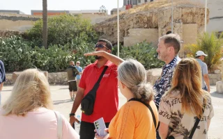 Tour guide leading a sightseeing group near ancient ruins and catacombs in Alexandria, Egypt.