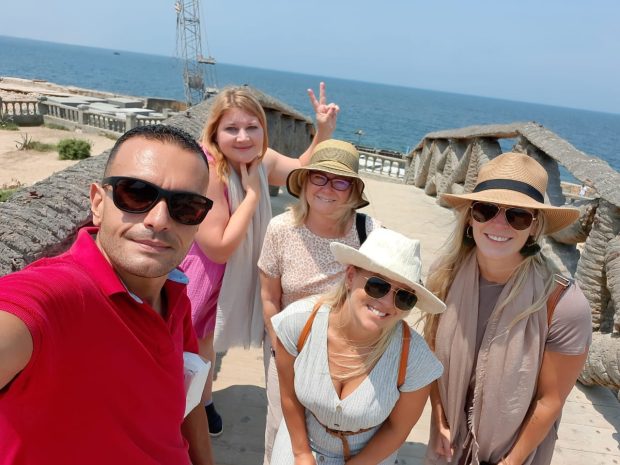 A smiling group taking a selfie on a stone bridge overlooking the Mediterranean Sea at Montaza Palace, Alexandria.
