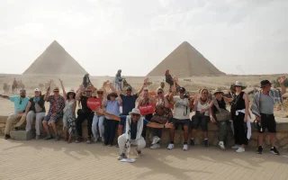 A group of happy tourists on a day trip to Cairo from Alexandria visiting the Giza Pyramids with Ramasside Egypt Tours.