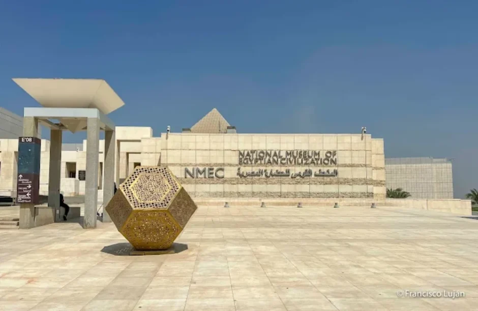 National Museum of Egyptian Civilization (NMEC) facade in Fustat with a golden geometric sculpture and clear blue sky.