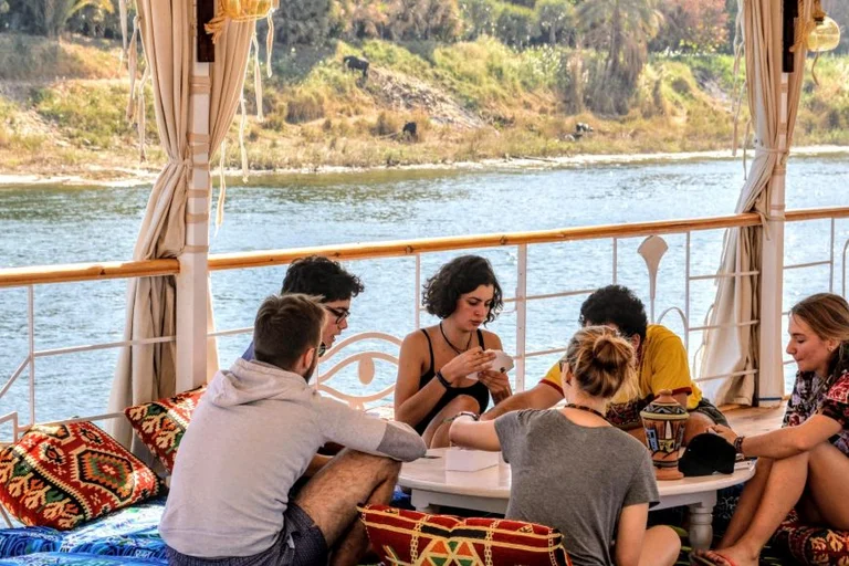 A group of friends enjoying a relaxing Nile River cruise vacation, sitting together on a traditional boat in Egypt.