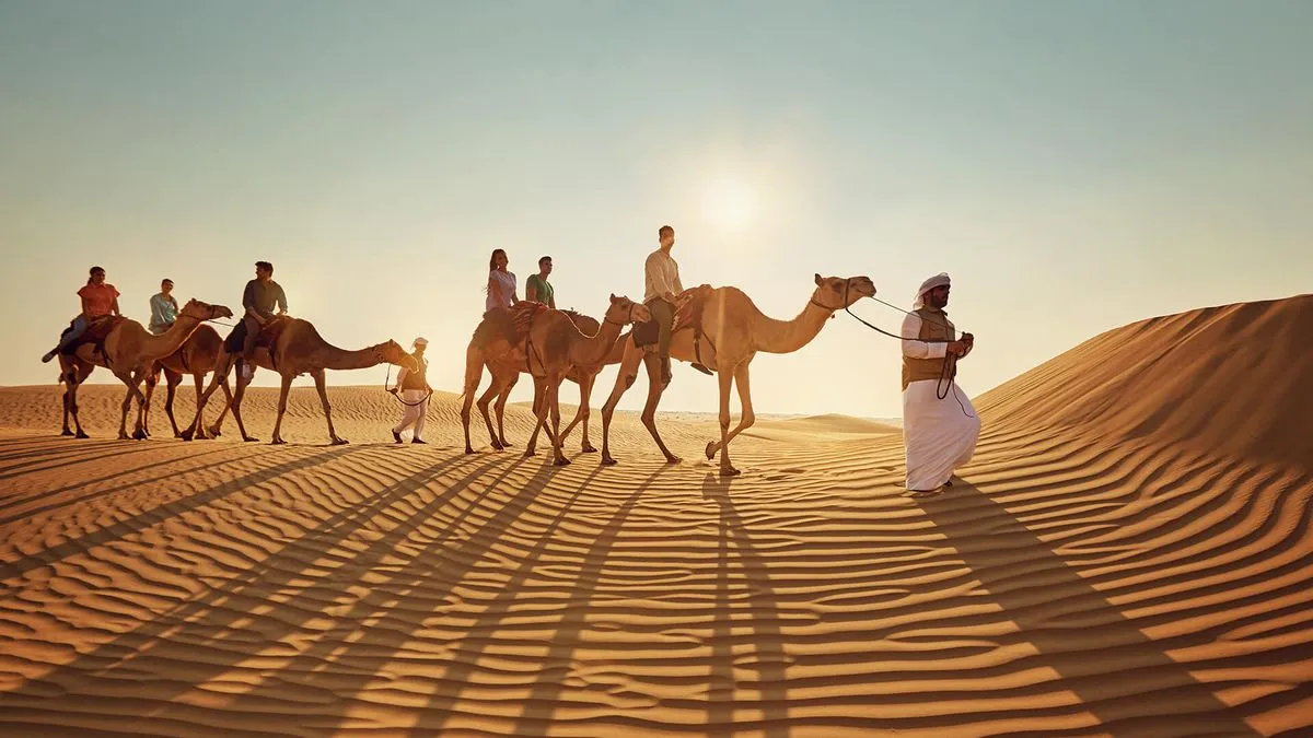 Camel caravan on desert sand dunes