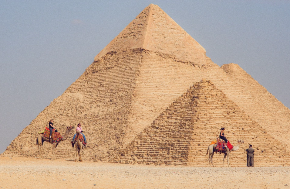 Travelers riding camels during Giza pyramids tours in Egypt