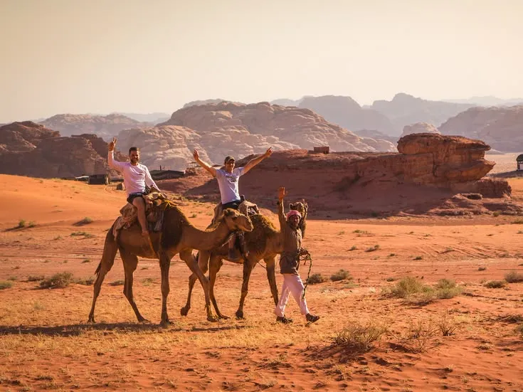 Tourists camel riding in desert mountains